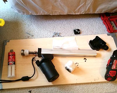 Parts of the power recliner's actuator assembly strewn on a piece of wood, a makeshift work surface.